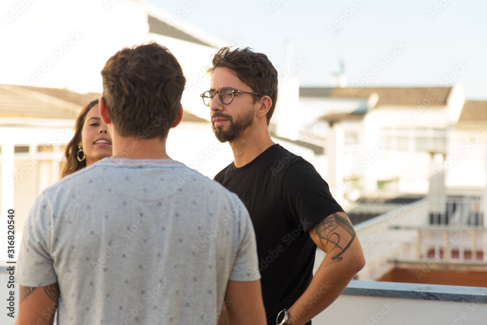 Focused friends talking on balcony. Thoughtful young people standing in circle and communicating. Communication concept Focused friends talking on balcony. Thoughtful young people standing in circle and communicating. Communication concept