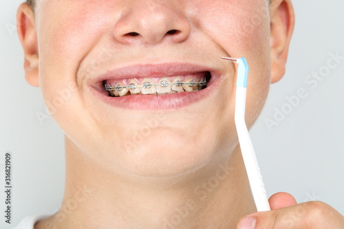 Young man with toothbrush on grey background