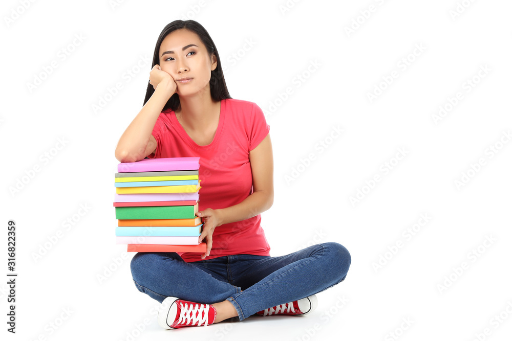 Young woman with stack of books sitting on white background