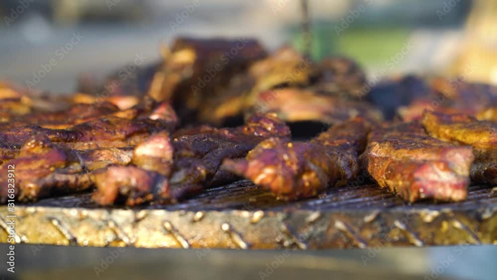 Pork ribs grilling on metal lattice at barbecue party