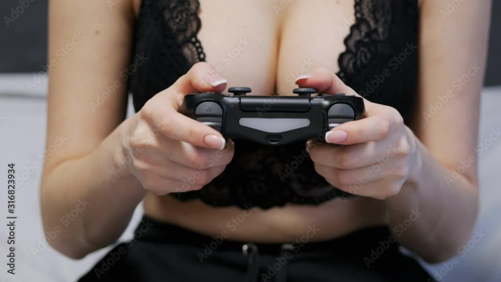 Close-up shot of sexy unrecognizable woman in a lace bra with gorgeous breasts playing games on the console on gamepad at home Close-up shot of sexy unrecognizable woman in a lace bra with gorgeous breasts playing games on the console on gamepad at home