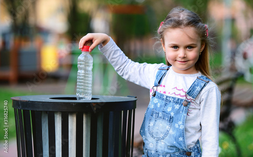 Little girl throwing bottle into the trash. Ecology concept
