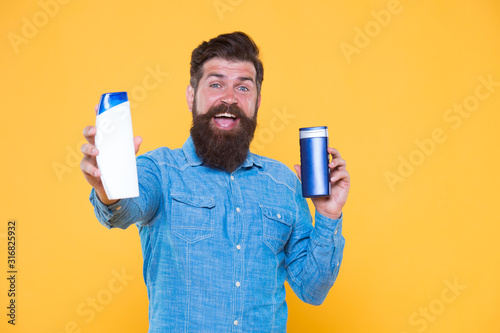 Good choice. Happy hipster hold shampoo and conditioner yellow background. Brutal hipster with hair care products. Bearded hipster with cleansing cosmetics. Grooming routine for hipster