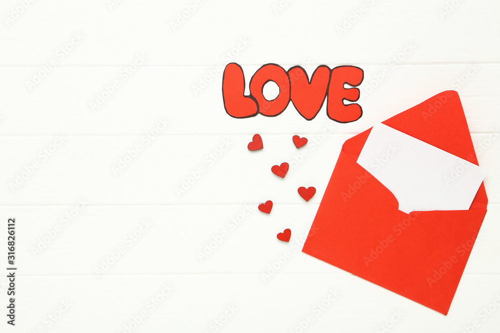 Paper envelope with hearts and word Love on white wooden table Paper envelope with hearts and word Love on white wooden table
