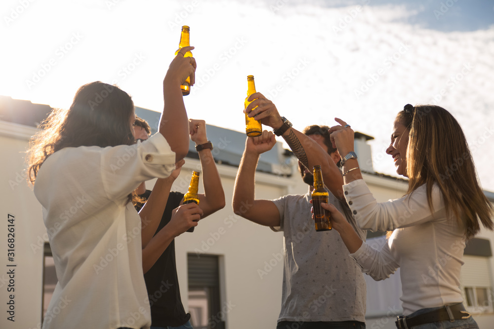 Low angle view of joyful friends dancing with beer. Group of smiling friends relaxing during party. Party concept