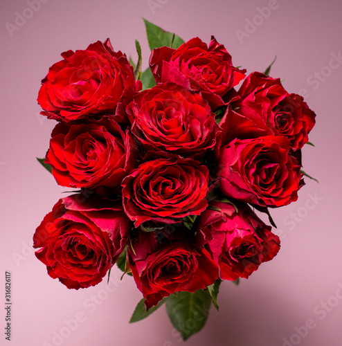 Red roses on a pink background. Valentine s Day greeting. Top view.