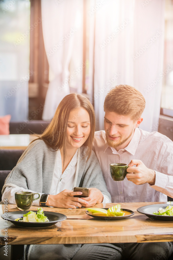 couple in a cafe smiling looking at the phone
