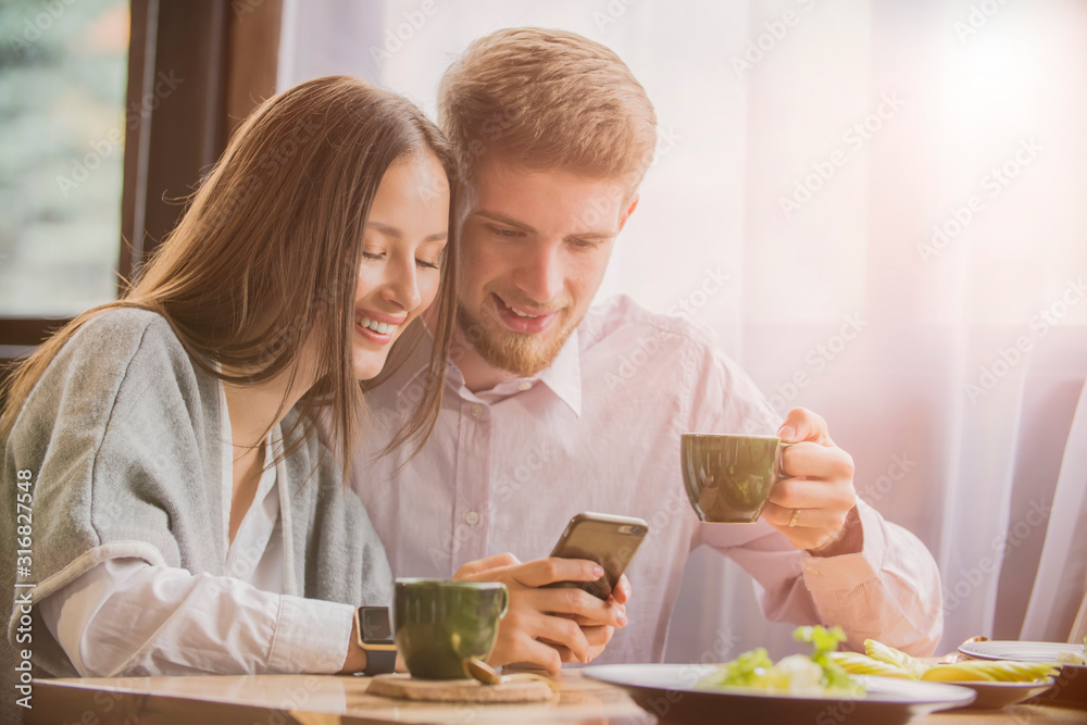 couple in a cafe smiling looking at the phone