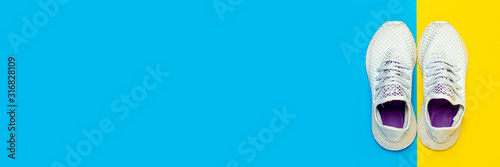 White running shoes on abstract yellow and blue background. Concept of running, training, sport. Banner. Flat lay, top view