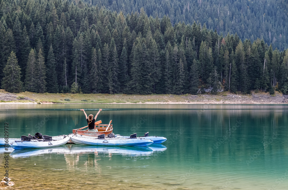 Black lake in Durmitor national park in Montenegro, boats on the lake reflected in water. Freedom and tranquility.