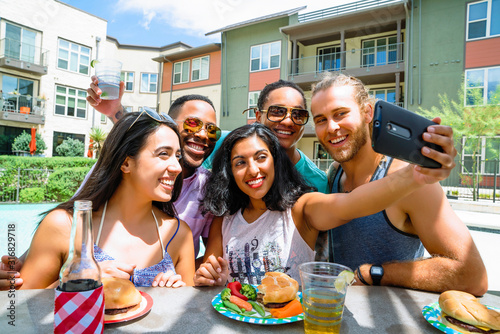 Friends at summer party laughing and taking selfie photo with cell phone