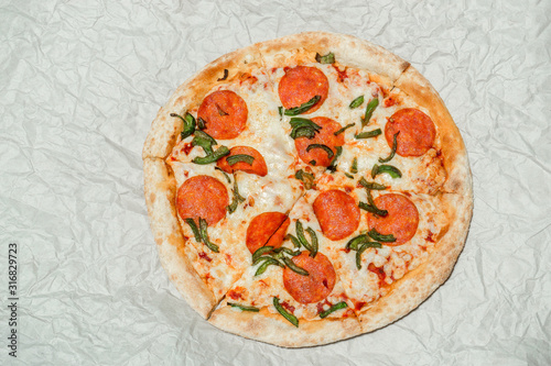 Delicious hot fresh Pepperoni pizza with mozzarella cheese and salami. On light paper background