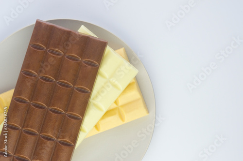  plate with three tiles of different chocolate on a light gray background Flat lay 