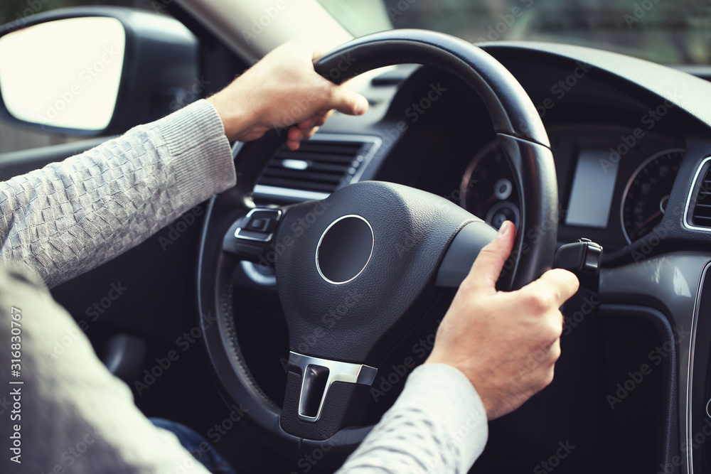 Man holding steering wheel and driving his car