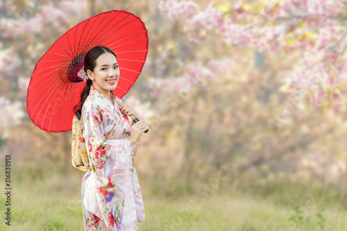 Canvas Print Japanese girl wearing a kimono holding a red umbrella