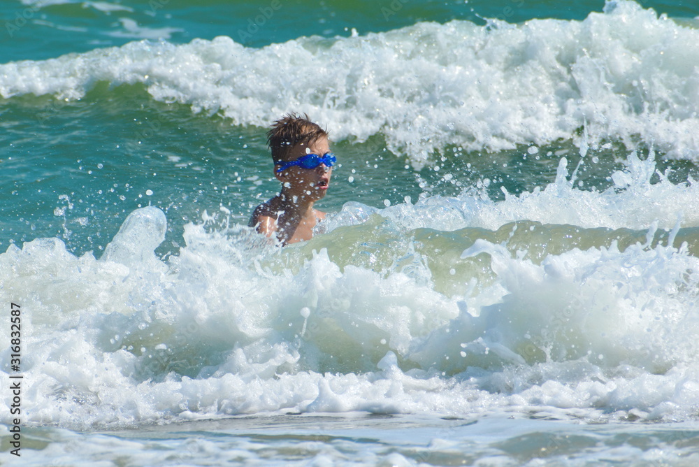 Child boy jumping on sea waves. Happy child in the ocean.