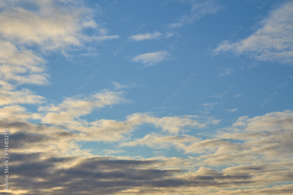 Cloudy sky with a parts of clear blue sky on a sunset. Natural background.
