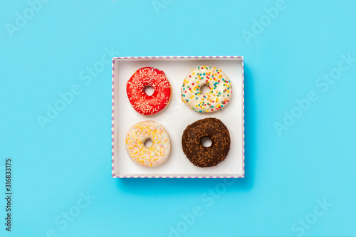 Tasty donuts in a box on a blue background. Concept of sweets, bakery, pastries, coffee shop. Banner. Flat lay, top view photo