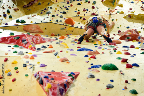 Unrecognizable man climbing wall in bouldering gym