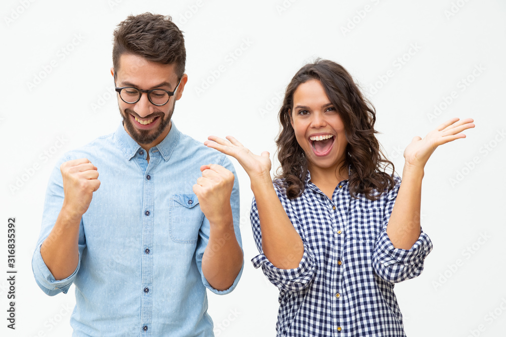 Content young couple celebrating success. Front view of cheerful young man and woman gesturing with hands and triumphing on white background. Winner concept Content young couple celebrating success. Front view of cheerful young man and woman gesturing with hands and triumphing on white background. Winner concept