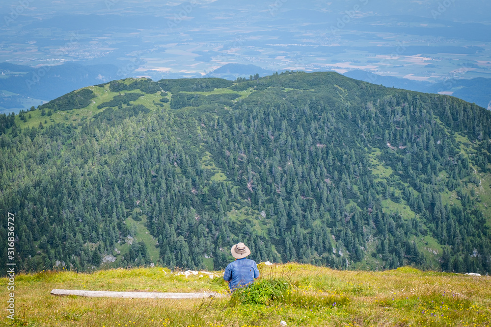 Summit of mountain Hochobir with man on bench, Carinthia, Austria