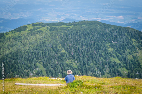 Summit of mountain Hochobir with man on bench, Carinthia, Austria photo