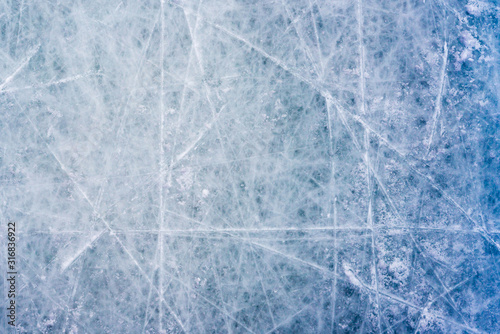 Ice background with marks from skating and hockey, blue texture of rink surface with scratches photo