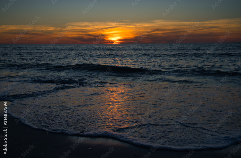 Wellen und Meer mit romantischen Sonnenuntergang und brennenden atemberaubenden Himmel am Horizont 