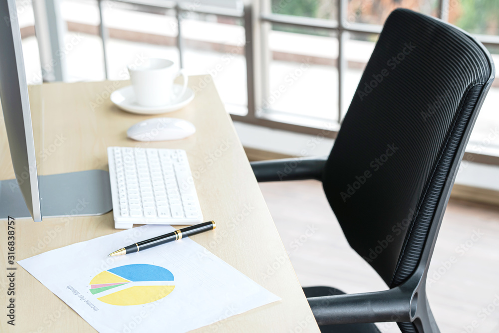 Business and workplace concept. Cup of hot coffee on work desk with computer keyboard and papers graphs in office working room. Business and workplace concept. Cup of hot coffee on work desk with computer keyboard and papers graphs in office working room.