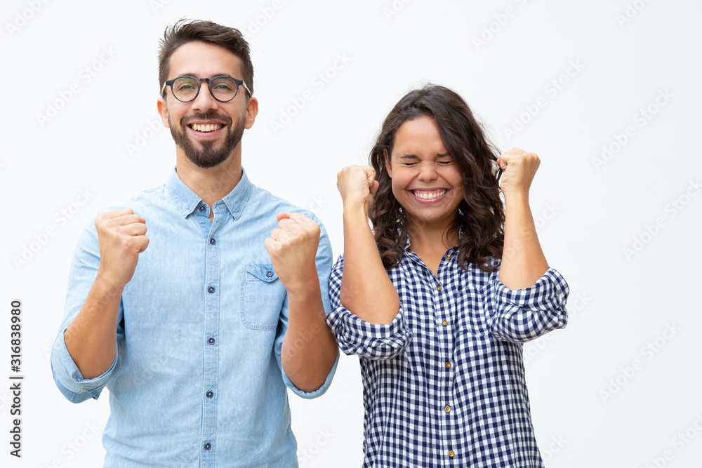 Excited young couple celebrating success. Front view of cheerful young man and woman raising fists and triumphing on white background. Winner concept Excited young couple celebrating success. Front view of cheerful young man and woman raising fists and triumphing on white background. Winner concept