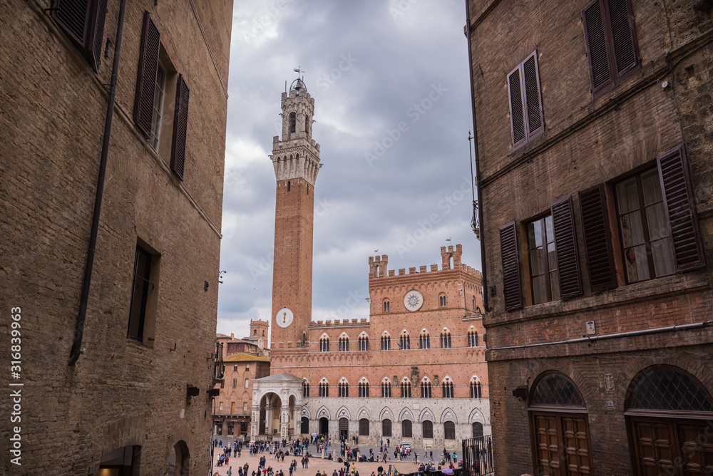 piazza del campo siena with peoples in downtown in tuscany in italy italian city with clouds sky in spring torre del mangia tower of palazzo di città historical palace architecture in central square