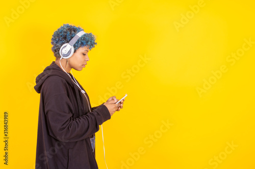 young girl with mobile phone and headphones isolated on color background