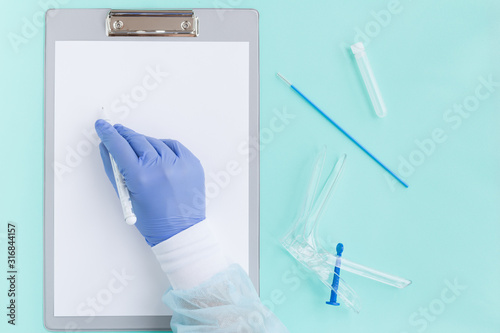 Flat lay: annual well woman exam, cervix cancer control. Gynecological speculum gyneas Cusco, cyto-cervical sampler brush-smear test, assay tube,folder for diagnosis,treatment, gloved doctor hand, pen photo