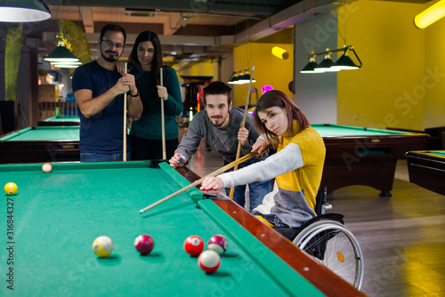 Disabled girl in a wheelchair playing billiards