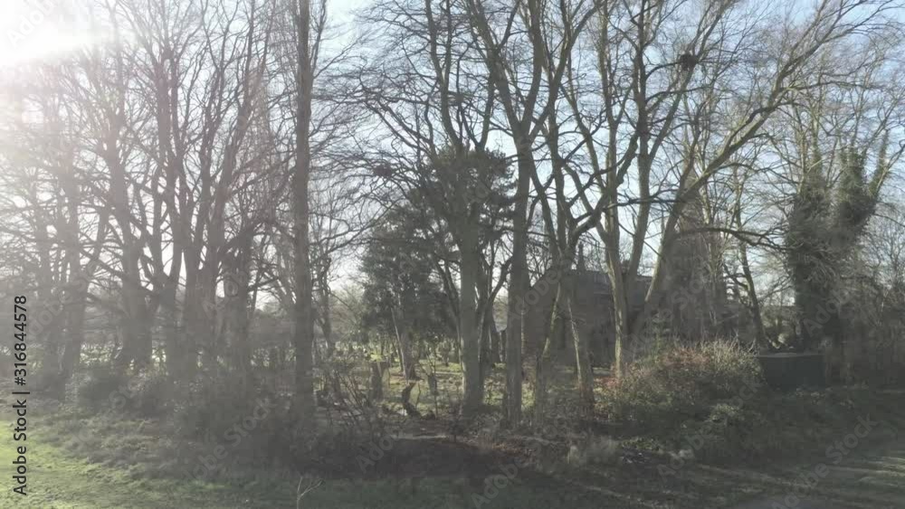 Rural English woodland village church hidden by trees in countryside sunrise sunlight. Wide orbit left over field. Rural English woodland village church hidden by trees in countryside sunrise sunlight. Wide orbit left over field.