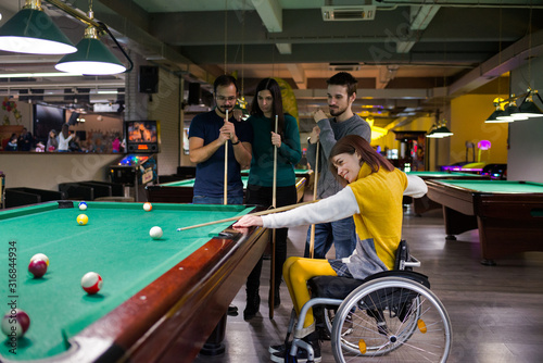 Disabled girl in a wheelchair playing billiards