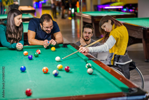 Disabled girl in a wheelchair playing billiards
