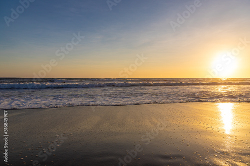 Ocean waves on the beach with beautiful sunset at one of the famous beaches of Canggu, Bali, Indonesia.