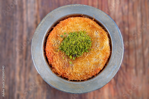 Turkish dessert kunefe, kunafa, kadayif with pistachio powder and cheese, served hot, very sweet. Turkish traditional dessert. photo