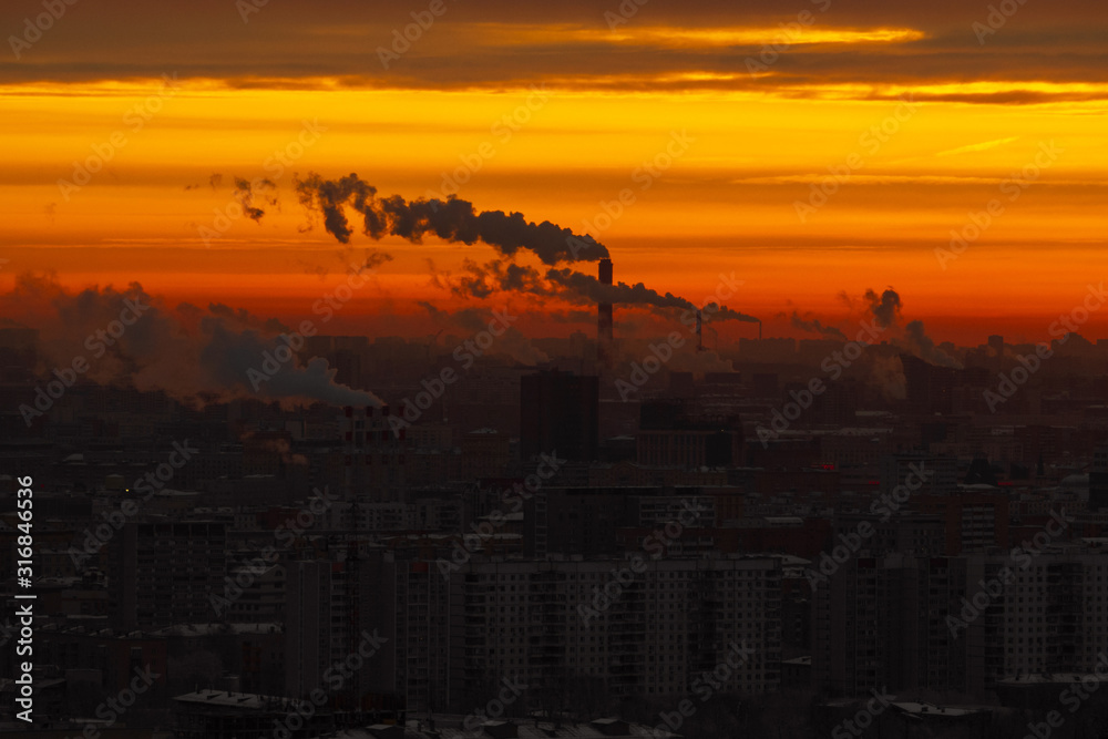 Sunrise over the city. Aerial view of Moscow, silhouettes of buildings in downtown with colorful lighting sunrise sky and soft clouds. Factories pipe, of which there are smoke