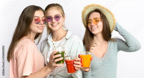 Cheerful young girls in sunglasses drinking fresh healthy smoothie