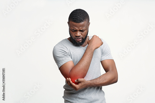 Young man having acute pain in elbow joint photo