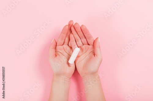Female hands hold tampon on a pink background