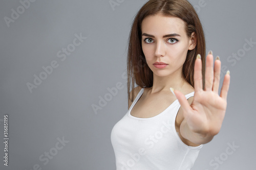 Serious young woman showing stop with her palm.