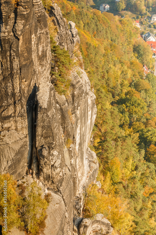 Rock formation in the Elbe Sandstone Mountains in autumn. Sunshine and trees with the Elbe valley. Climbing and hiking near the Bastei bridge in Saxon Switzerland.