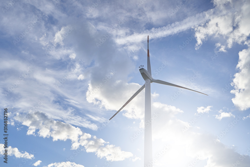 Large wind farm with blades on the background of the evening sky with clouds and the sun. Ecology and green technology concept Large wind farm with blades on the background of the evening sky with clouds and the sun. Ecology and green technology concept