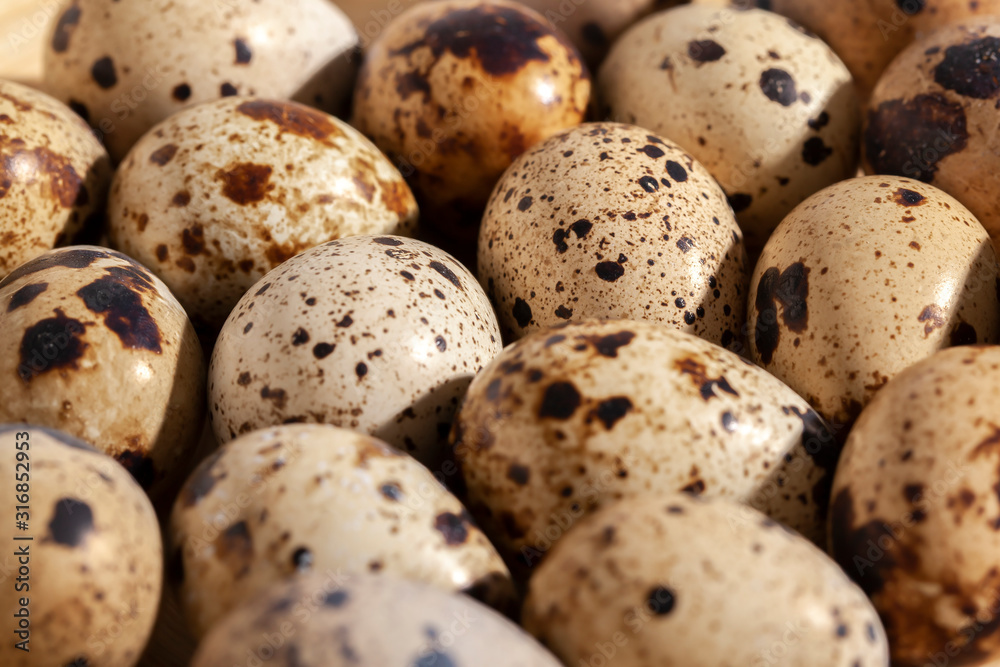 Obraz premium Quail eggs stacked on a yellow bamboo plate.