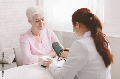 Doctor measuring blood pressure of senior female patient