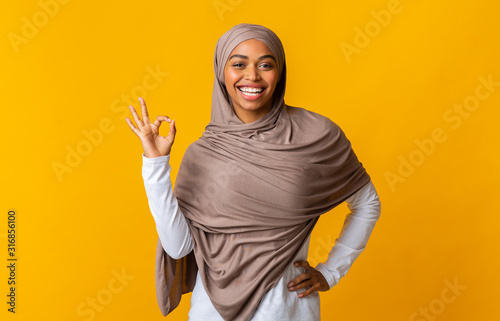 Cheerful afro muslim girl in headscarf showing ok sign
