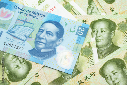 A close up image of a twenty Mexican peso bank note with Chinese one yuan bills in macro